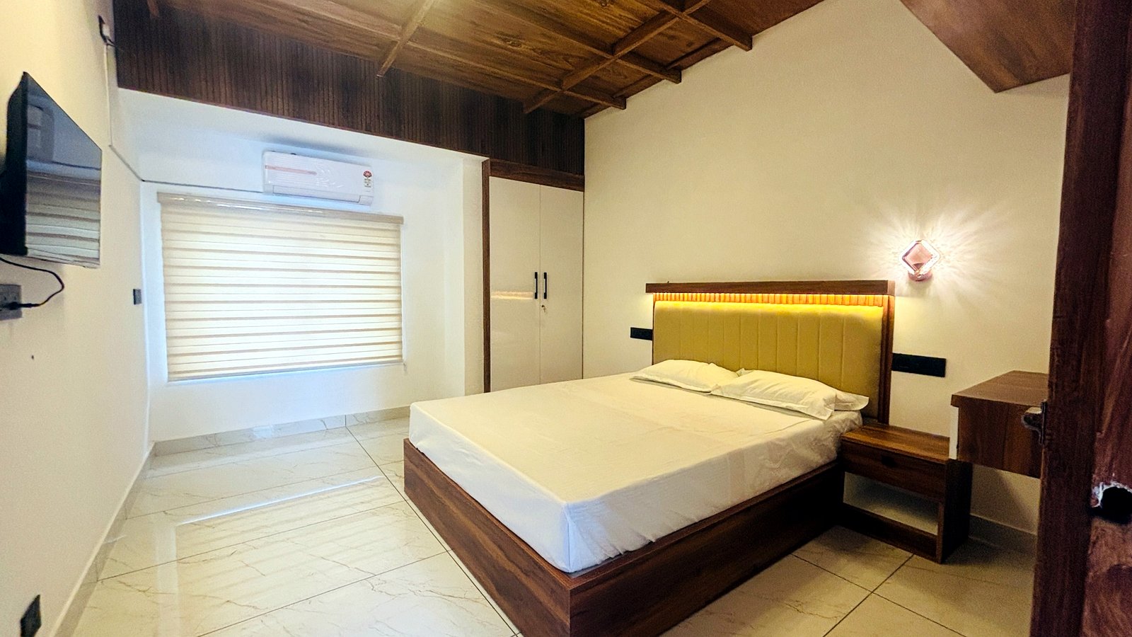 Kerala Spices Homestay deluxe room with AC TV wooden ceiling and lit headboard